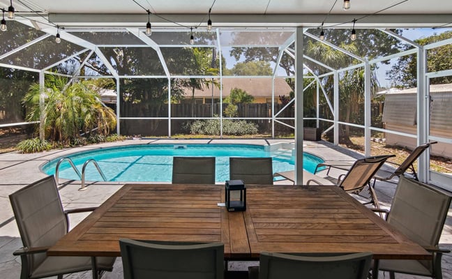 Collage of vacation rental property showing beachfront dock with palm trees, modern bedroom, open-plan living space, twin bedroom with ocean view, and covered